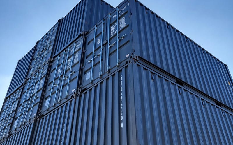 Shipping containers stacked against a dusk sky, representing repeat freight.